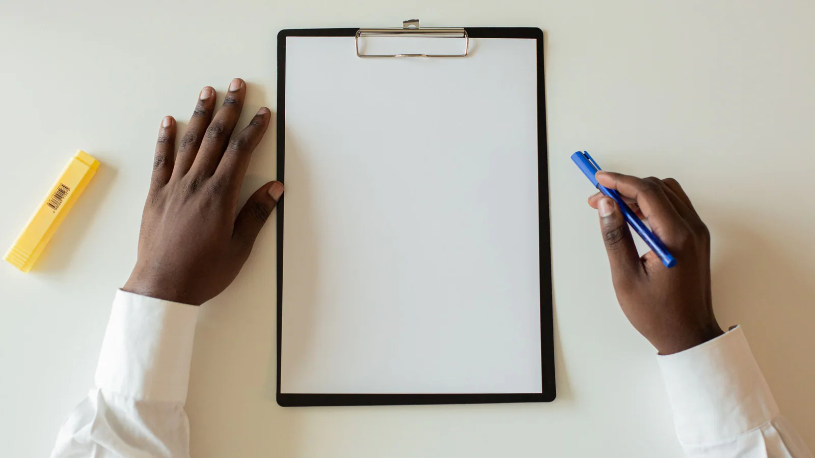 Hands beside a blank clipboard and pen