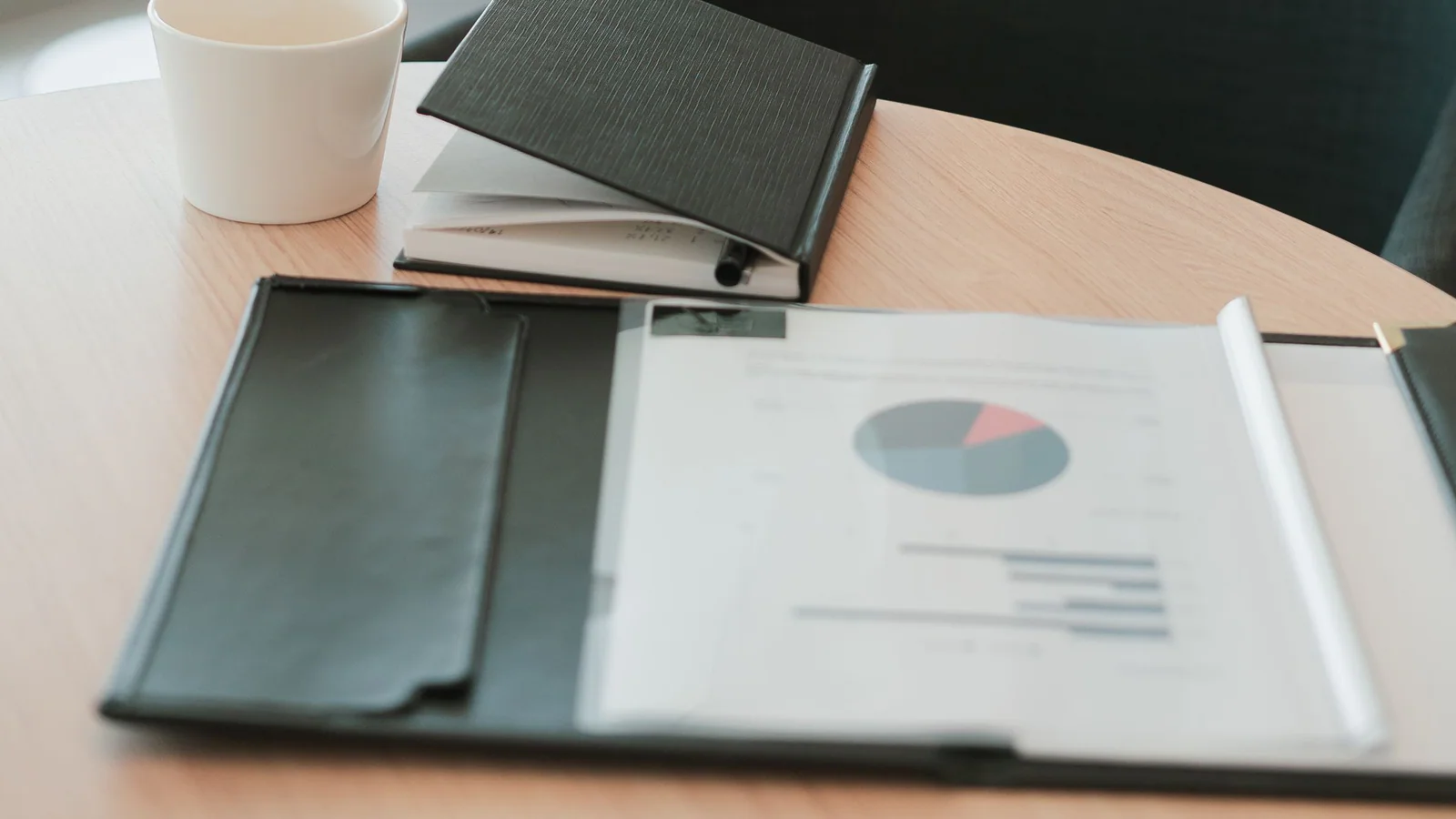 Business report, notebook and pen arranged on a modern office table