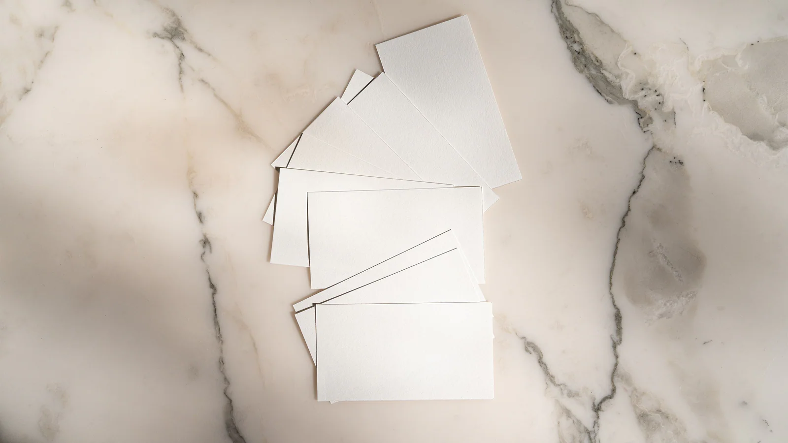 Blank white identity cards arranged on a pale marble surface