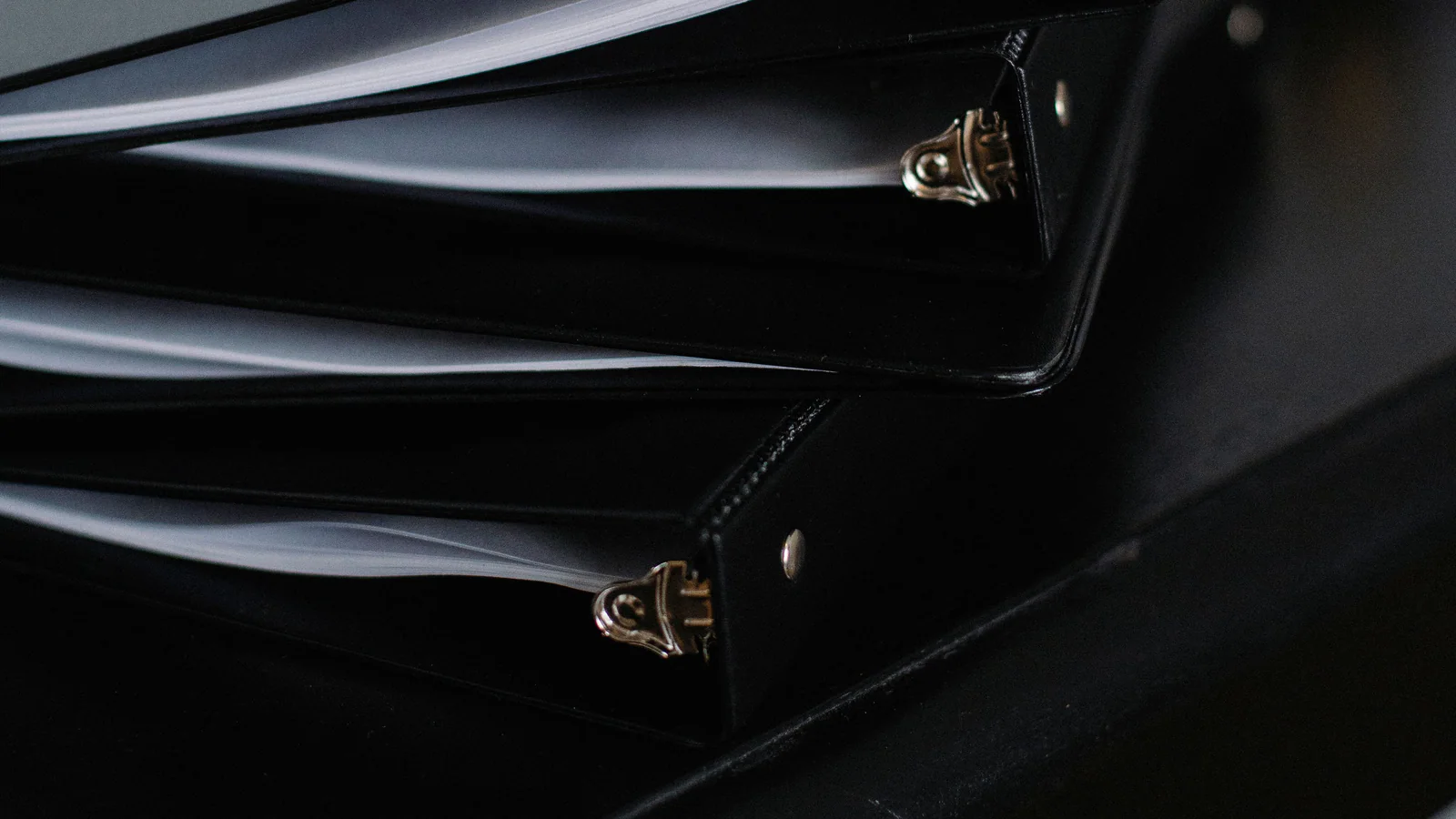 Stacked black document binders on a dark office desk
