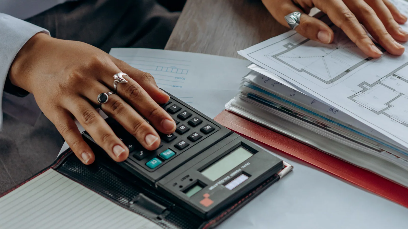 Person comparing property plans with a calculator