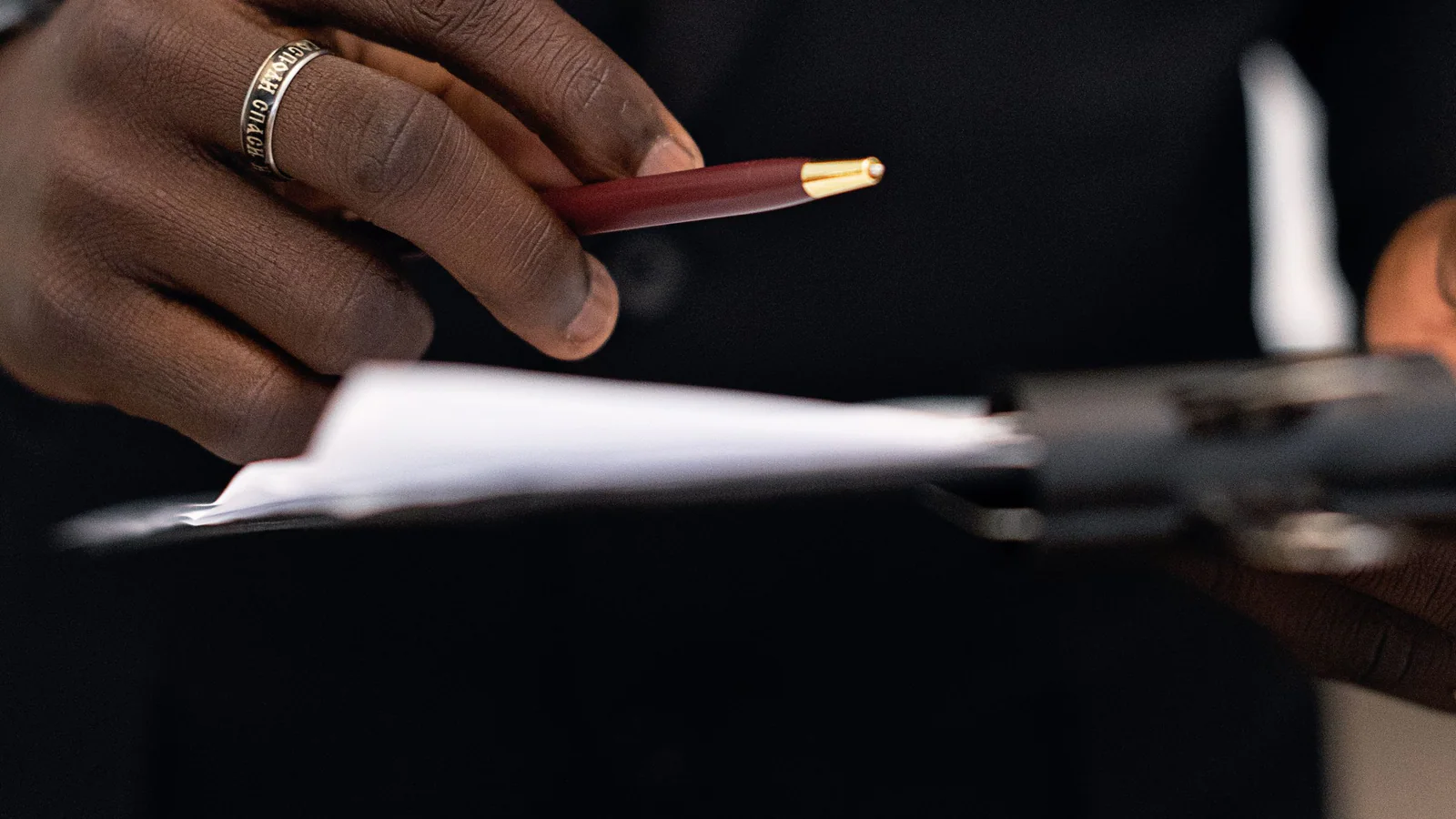 Person holding a pen above blank documents