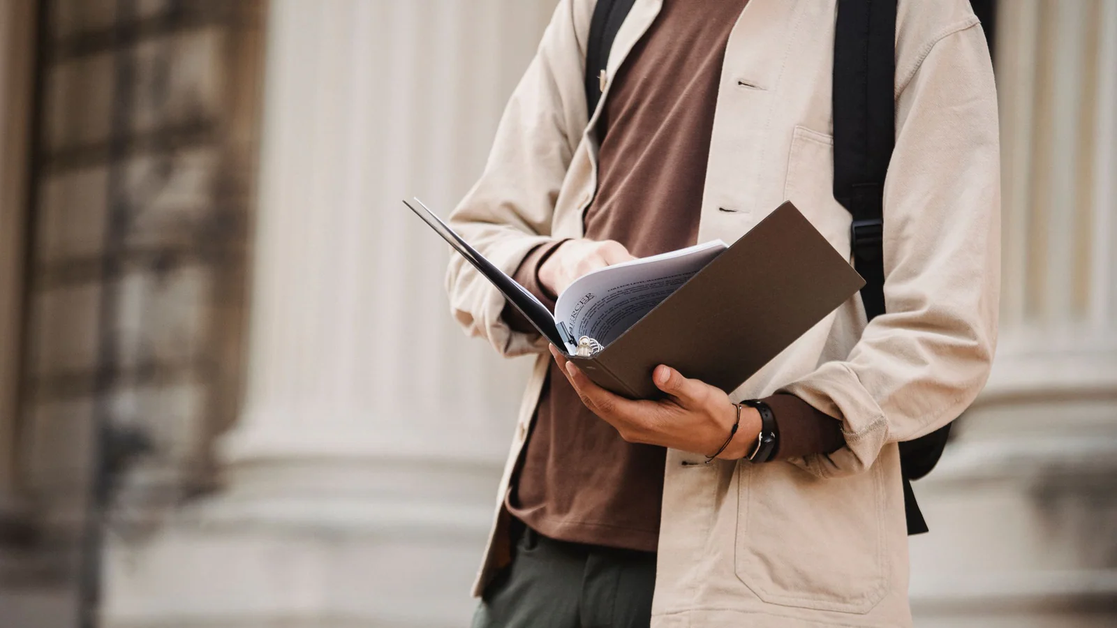 Student reviewing a folder outside a university building