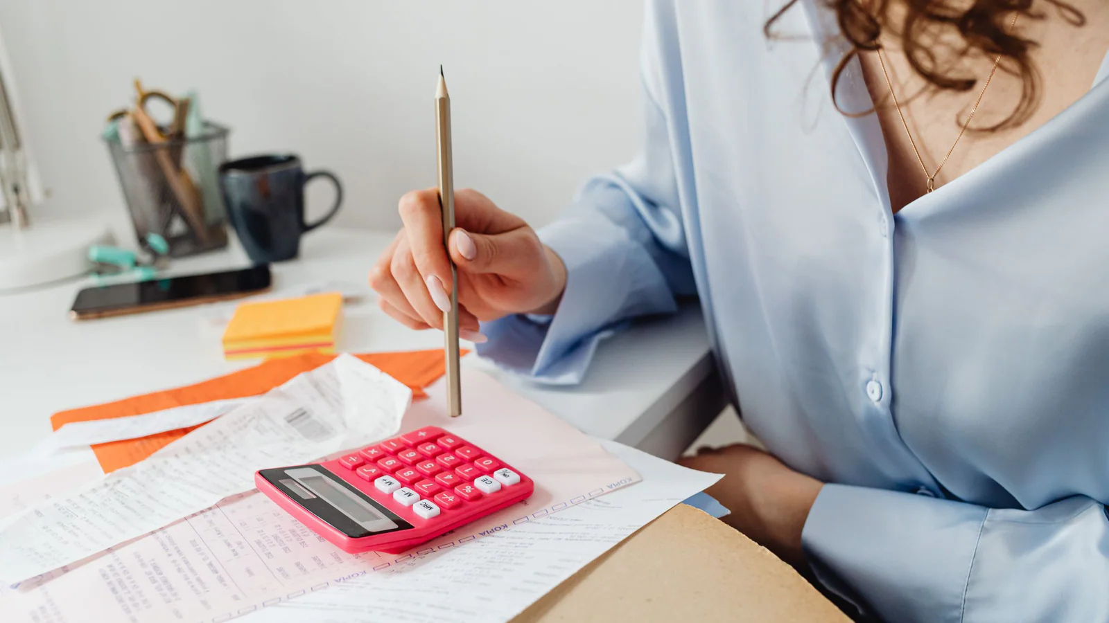 Person calculating amounts from documents at a desk
