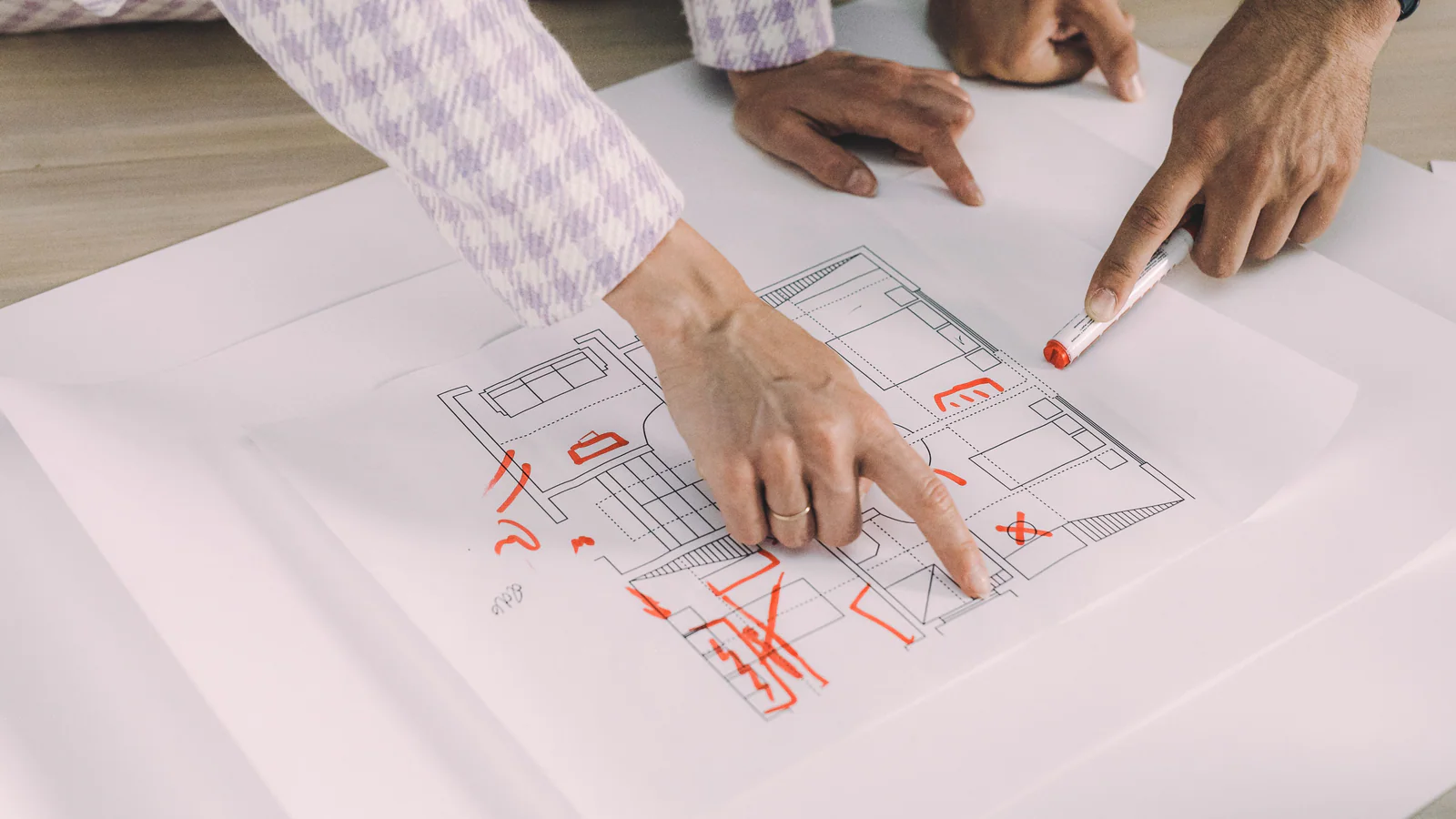 Three people pointing to a marked floor plan