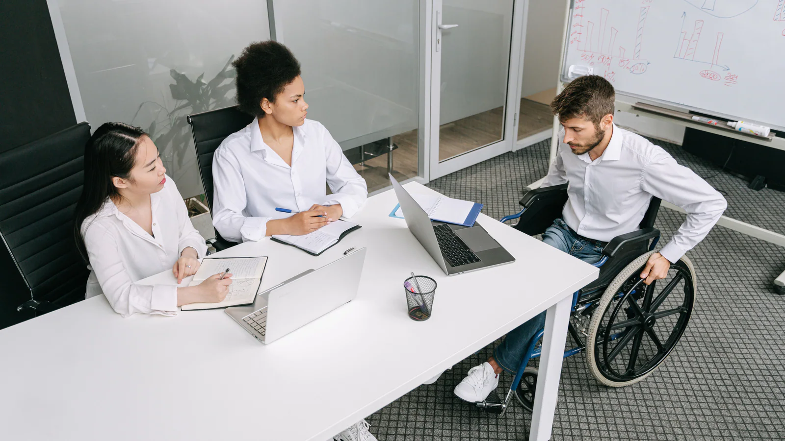 Three colleagues discussing work around a table in an office