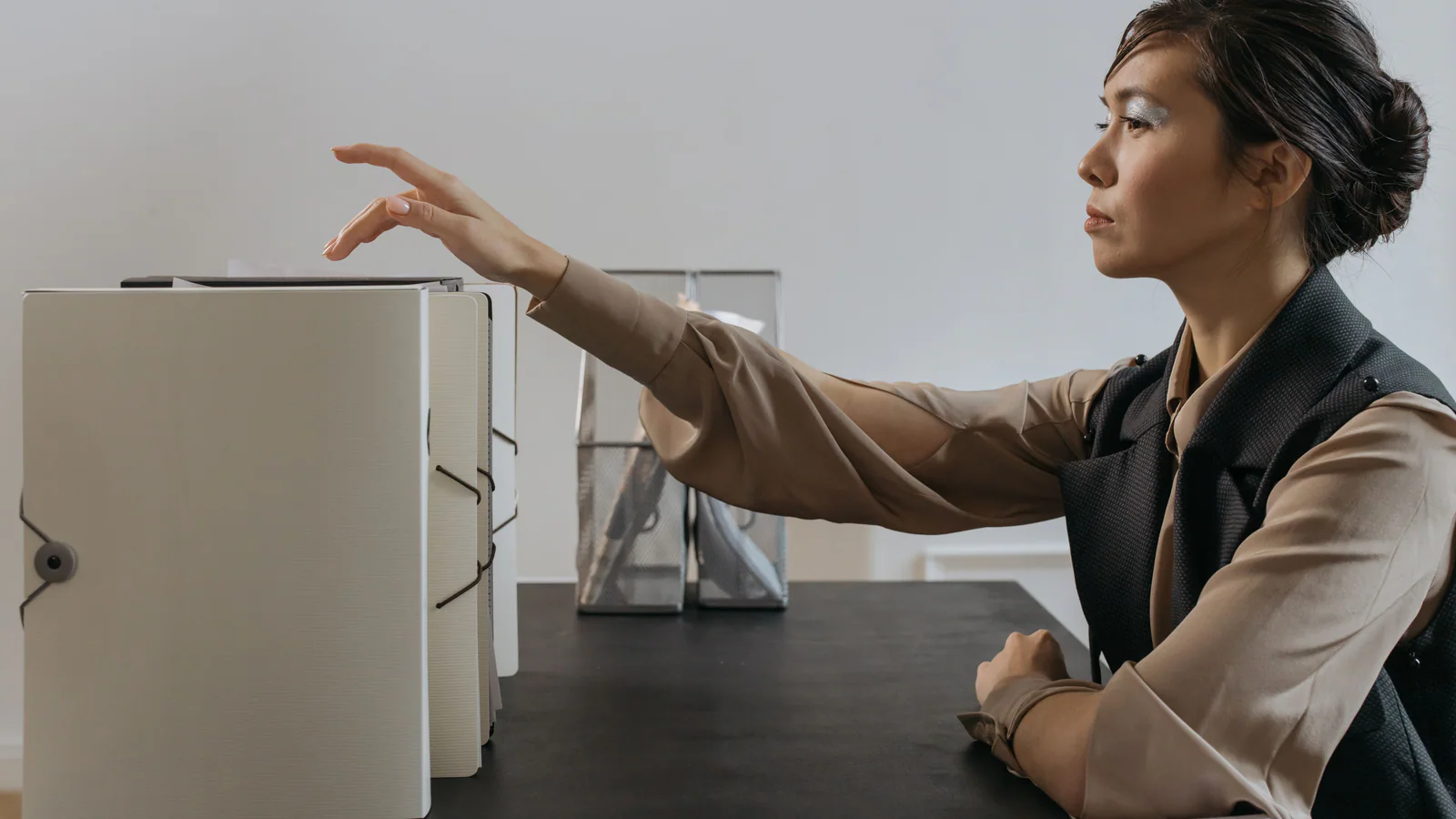Person reaching for closed document folders at an office desk
