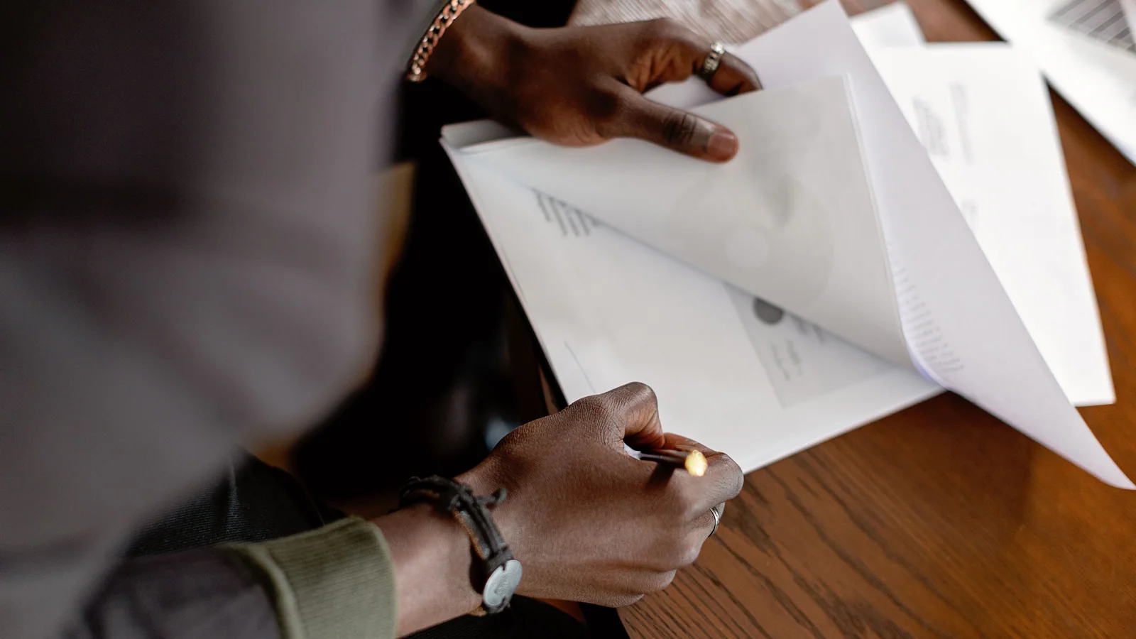 Anonymous person reviewing papers in a folder at a table