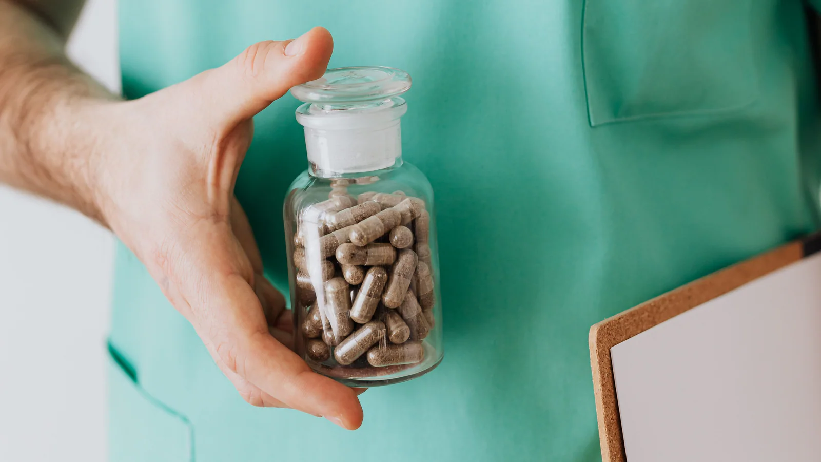 Healthcare worker holding an unlabelled medicine bottle beside a blank clipboard