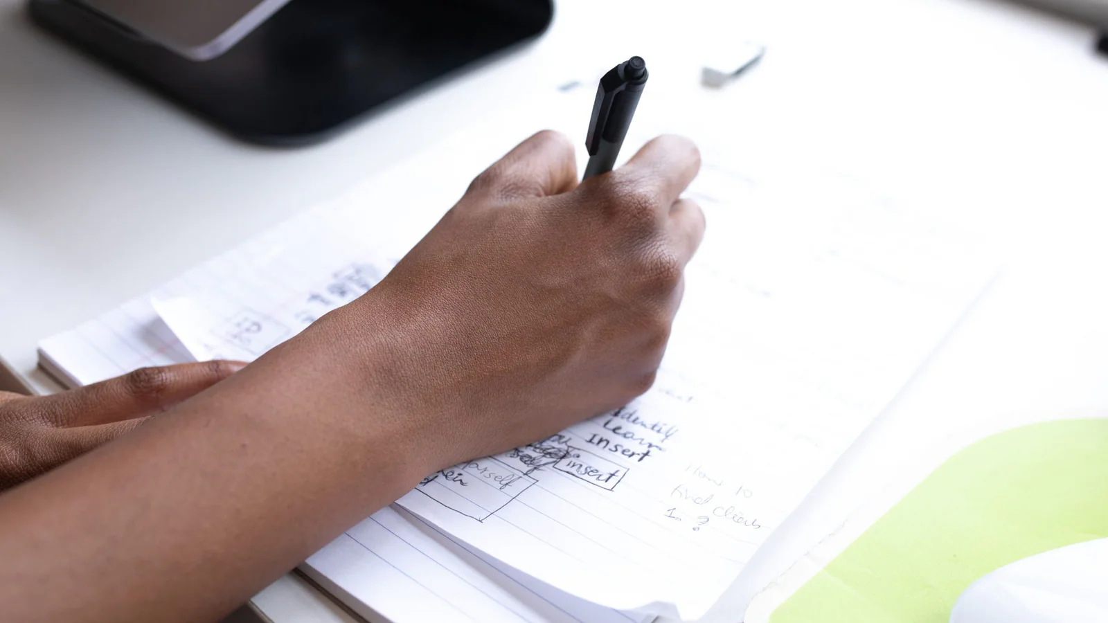 Cropped hands writing notes on papers at an office desk