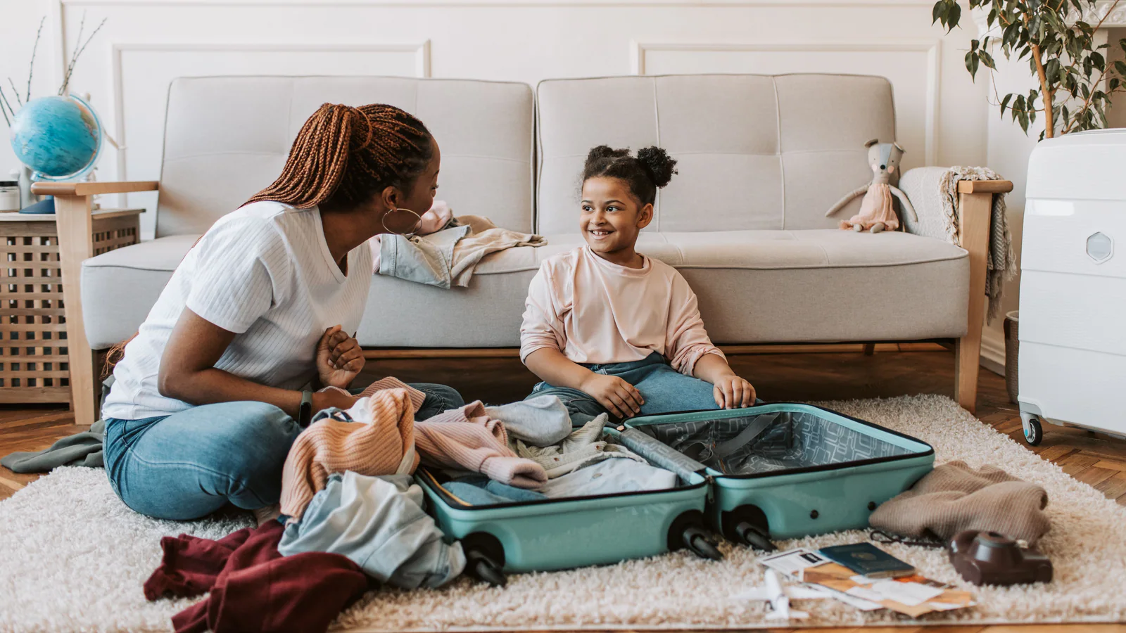 Parent and child packing an open suitcase together at home